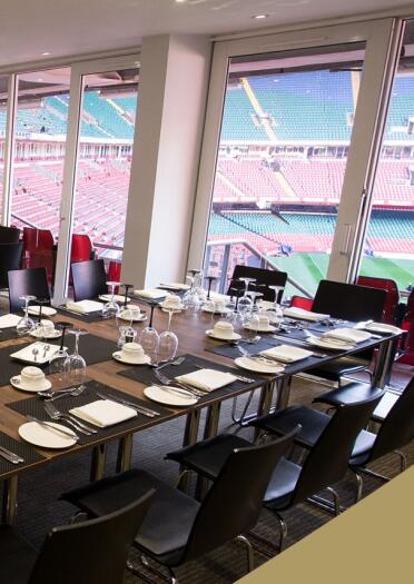 Dining tables set out in a VIP box overlooking a sporting stadium.